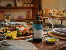 A Savour Society box unpacked across a wooden table with produce, bread and linen